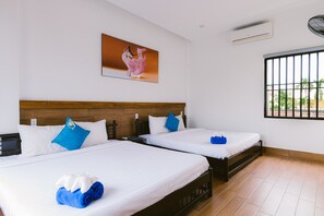 A hotel room with two beds, a wooden headboard, a large window with bars, and a painting on the wall.