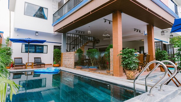 A modern pool area with a clear pool, lounge chairs, and potted plants. - Hoi An Nguyen Homestay (Da Nang)