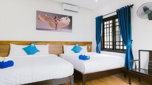 A hotel room with two beds, a wooden headboard, a window with blue curtains, a wall-mounted air conditioner, and a framed picture above the beds. - Hoi An Nguyen Homestay (Da Nang)