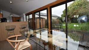 Une cuisine moderne avec des meubles en bois, une table à manger en verre et des chaises.
