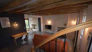 Un salon moderne avec un escalier en bois, une cheminée et un téléviseur.