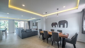 Una sala de estar moderna con comedor, un sofá y una mesa preparada para seis personas.