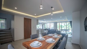 Un comedor moderno con una larga mesa de madera dispuesta para seis personas, rodeada de sillas grises.