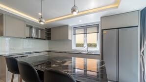 Una cocina moderna con una isla grande, sillas negras y un horno empotrado.