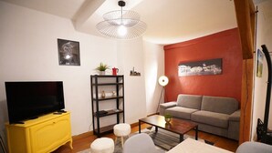 Una sala de estar con un sofá, una mesa de centro, un televisor sobre un mueble amarillo y una pared de acento roja.