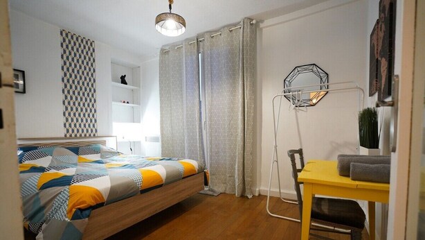 A bedroom with a bed, a desk, a chair, a lamp, and a shelf with decorative items. - Cosy T3 with terrace, near the Loire (Orléans)