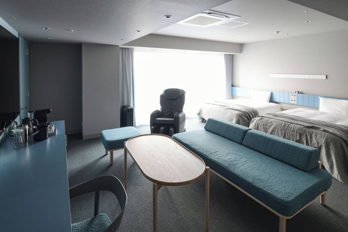 Una habitación de hotel moderna con una cama grande, un sofá, un escritorio y una silla.