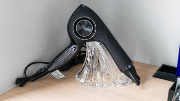 A black hair dryer with a clear plastic stand on a wooden surface.