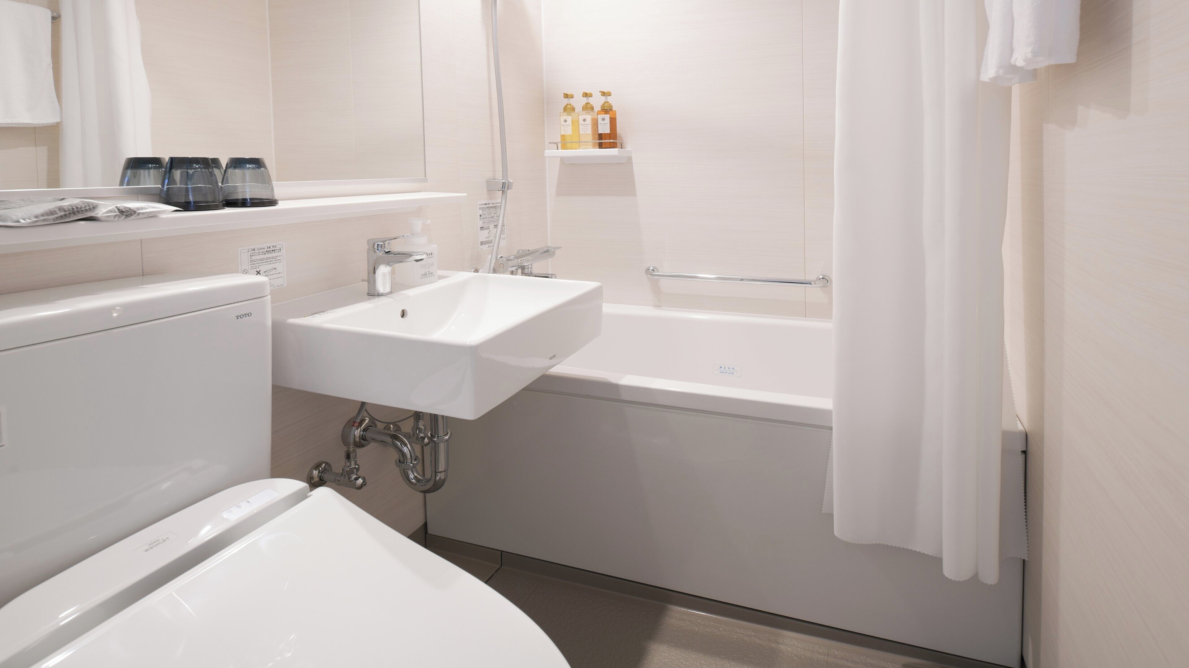 A modern bathroom with a white sink, a bathtub, and a toilet. There are toiletries on a shelf above the sink.