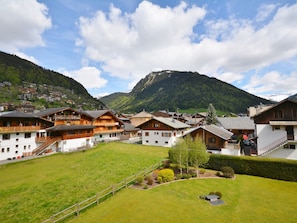 A mountainous village with traditional wooden houses, a grassy field, and a mountain in the background. - Spacious Studio for 4 with Balcony, Near Ski Lifts & Shops, Morzine Center (Morzine)
