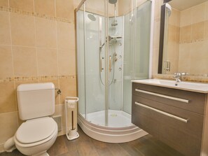 A bathroom with a glass-enclosed shower, a toilet, and a vanity with a mirror.