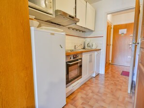 A compact kitchen with a refrigerator, oven, and a coffee maker.