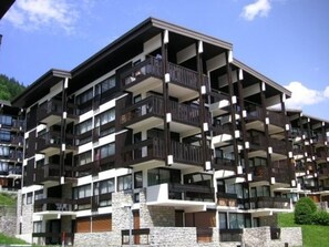 A multi-story hotel with balconies, stone facade, and a clear sky.