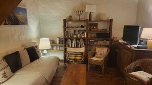 Ein gemütliches Wohnzimmer mit einer Couch, einem Holztisch, einem Bücherregal und einem Fernseher.