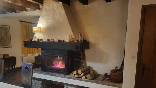 Ein gemütliches Zimmer mit Kamin, einem Holztisch und einem Stuhl.