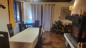 Ein gemütliches Zimmer mit Kamin, Esstisch und Weihnachtsbaum.