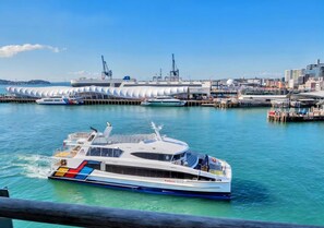 Un yate blanco con franjas de colores atracado en un puerto deportivo con un edificio moderno al fondo.