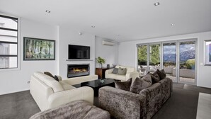 Una sala de estar moderna con chimenea, asientos cómodos y un amplio ventanal con vistas panorámicas.