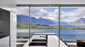 Una cocina moderna con un amplio ventanal con vistas a un lago y montañas.
