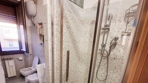 A modern bathroom with a glass-enclosed shower, a toilet, and a sink. - Penthouse with stunning views of St. Paul's Basilica (Roma)