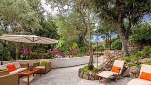 An outdoor patio area with seating arrangements, a stone wall, and lush greenery. - Charming Villa, Ischia, Punta Caruso, Forio, n.3 (Forio)