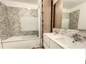 Une salle de bain moderne avec une baignoire sur pieds, un meuble-lavabo et un miroir.