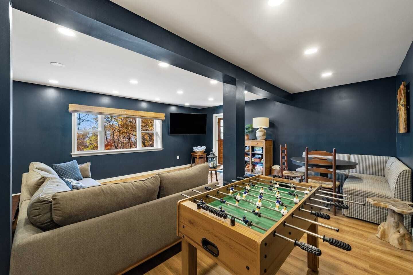 Una sala de estar acogedora con una mesa de fútbol de mesa, un sofá y una televisión.