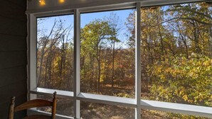 Ein Zimmer mit großem Fenster und Blick auf ein bewaldetes Gebiet.