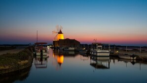 A windmill at sunset with boats docked nearby.