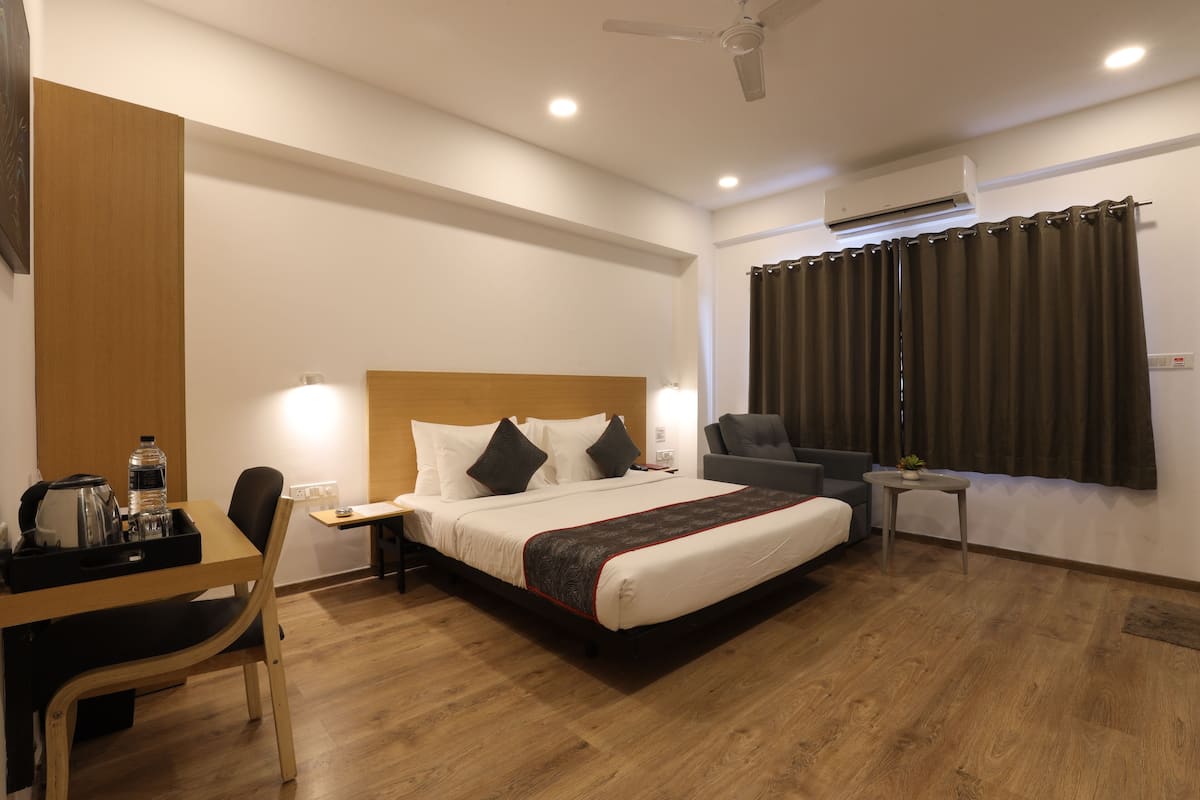 Una habitación de hotel con cama, escritorio con silla, una mesita y un sofá.