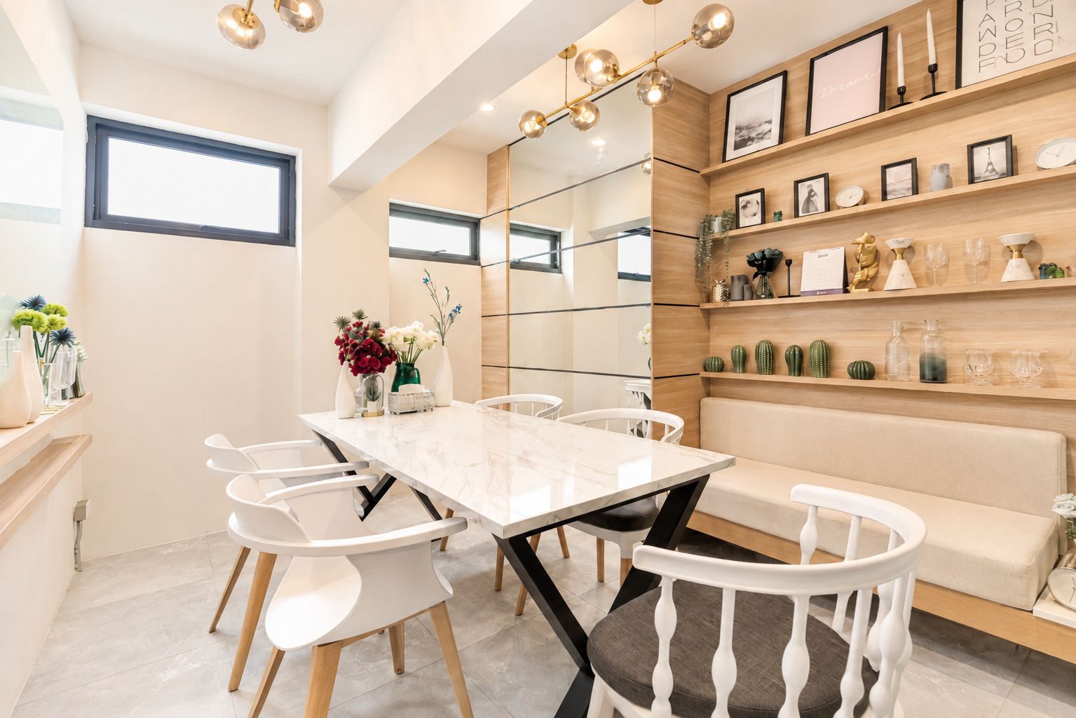 Un comedor moderno con una mesa de mármol, sillas blancas, un banco de madera y un estante de pared con adornos.