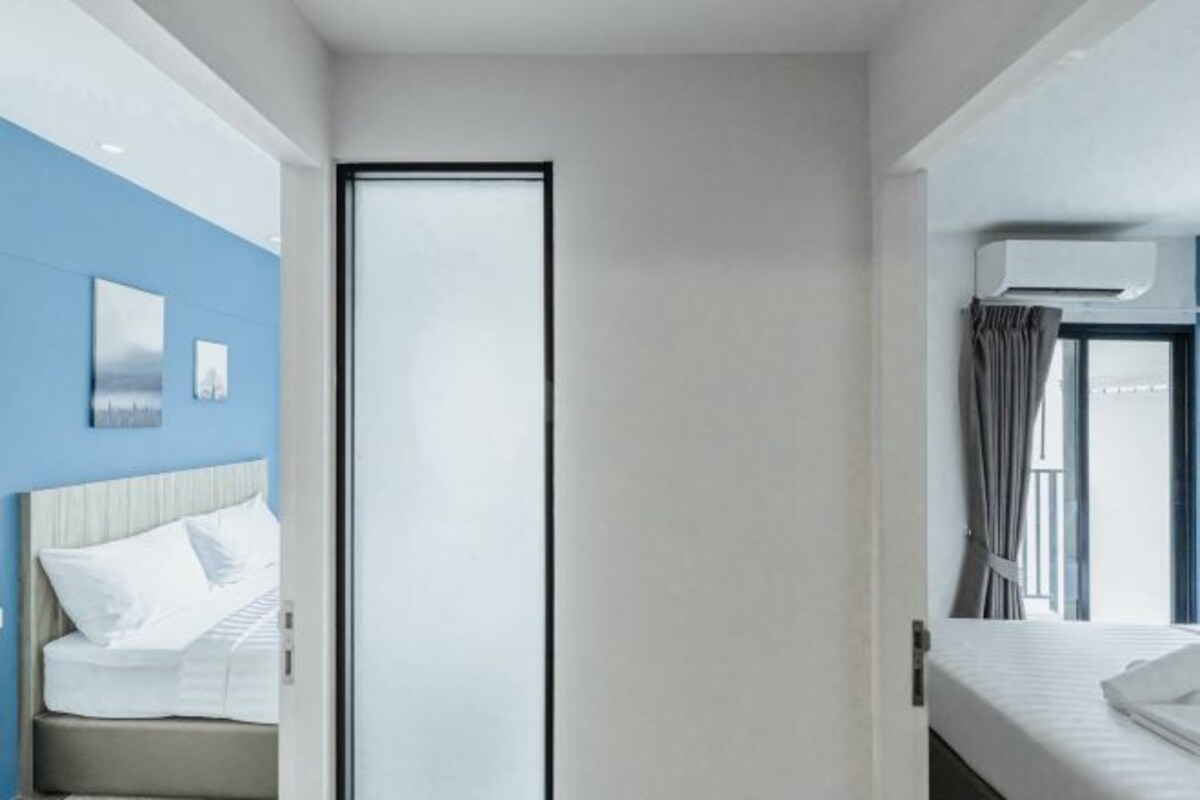 A hotel room with a bed, a wardrobe, a window with curtains, and a wall-mounted air conditioner.