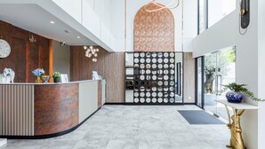 A modern reception area with a curved reception desk, a wall-mounted clock, and a decorative plant. - ABC@48 Hotel & Service Apartment (Bangkok)