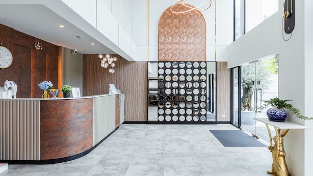 A modern reception area with a curved reception desk, a wall-mounted clock, and a decorative plant. - ABC@48 Hotel & Service Apartment (Bangkok)
