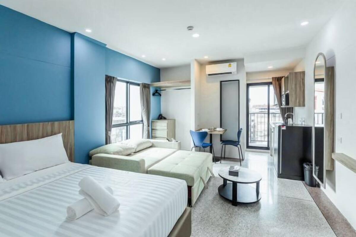 A hotel room with two beds, a desk, a chair, and a small table.