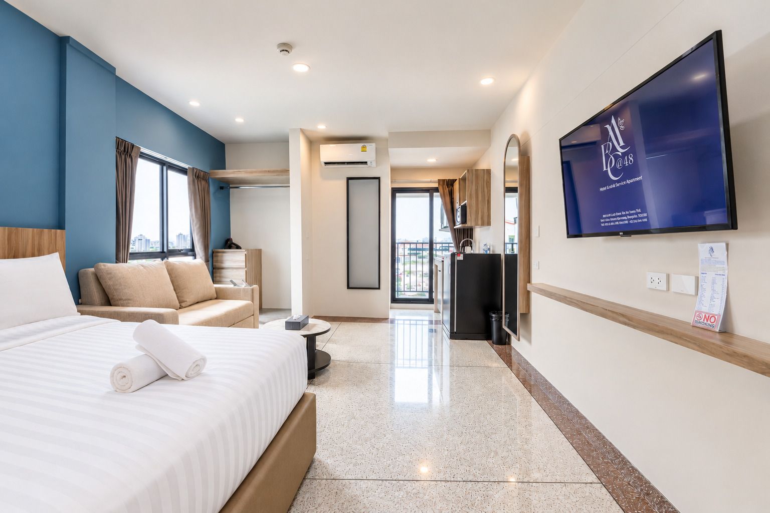 Una habitación de hotel con cama, sofá, televisión y vistas a la ciudad.