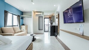 A hotel room with a bed, a sofa, a TV, and a balcony. - ABC@48 Hotel & Service Apartment (Bangkok)