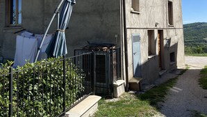 A two-story building with a tiled roof, a small porch, and a gravel path leading to the entrance. - Quiet apartment in the coutryside of Marche (Cagli)