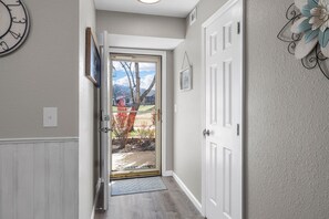 A hallway with a door leading to a view of trees and a clear sky. - No-Step 2BR | 2 Kings | Indoor Pool + Hot Tub (Branson)