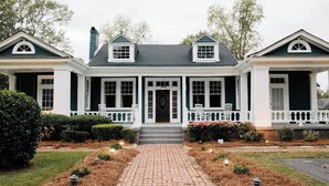 A two-story house with a central entrance, white trim, and a brick pathway leading to the front door.
