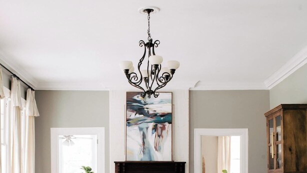 A living room with a fireplace, two white armchairs, a sofa, a coffee table, and a chandelier.