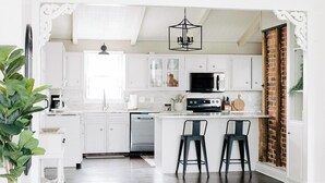 A modern kitchen with white cabinets, a black microwave, and a central island with two bar stools.