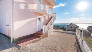 Ein pinkfarbenes Gebäude mit Balkon und einer Treppe, die zum Eingang führt.