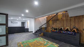 Un área de recepción con una escalera de madera, un mostrador de recepción y una alfombra colorida.