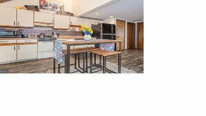 A modern kitchen with wooden cabinets, a central island with stools, and a microwave. - In the Heart of Deep Creek, Wood Fire, steps Lake, Coffee, Pizza, minutes Whisp, (Oakland)