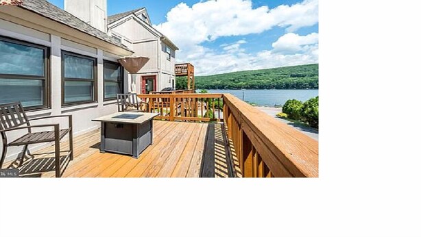 A wooden deck with a table and chairs, overlooking a lake. - In the Heart of Deep Creek, Wood Fire, steps Lake, Coffee, Pizza, minutes Whisp, (Oakland)