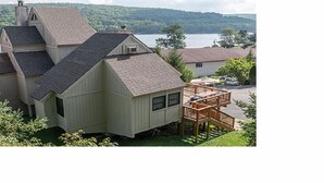A house with a sloped roof, a deck, and a view of a lake. - In the Heart of Deep Creek, Wood Fire, steps Lake, Coffee, Pizza, minutes Whisp, (Oakland)