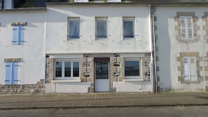 Un bâtiment à deux étages, doté d’une façade blanche, de nombreuses fenêtres et d’une porte bien visible.