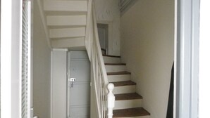 Un escalier avec des marches en bois et des rampes blanches menant à une porte située en haut.