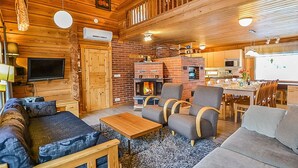 A cozy log cabin interior with a fireplace, wooden furniture, and a dining area.